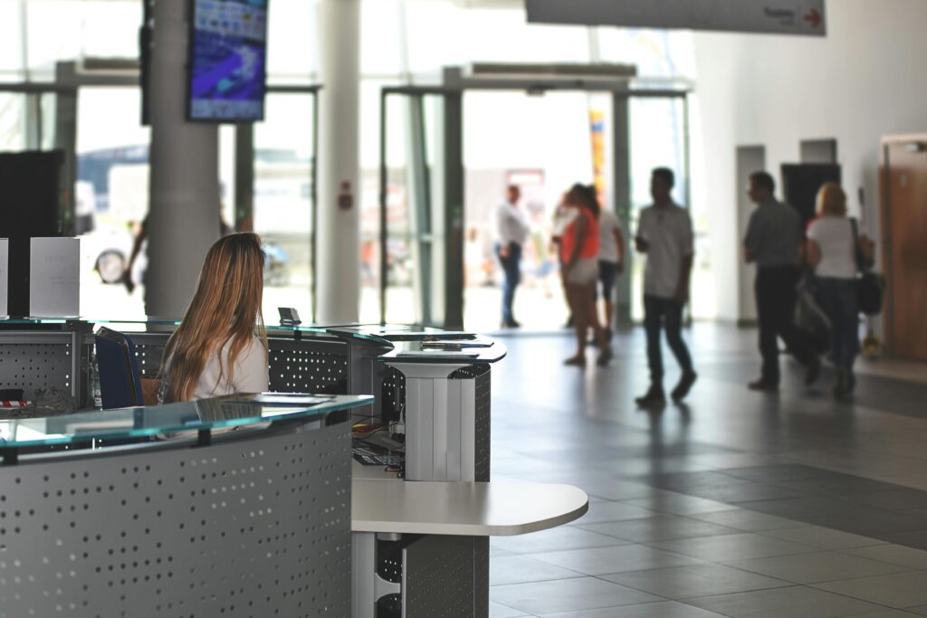 pexels-photo-518244-518244 A bustling office reception area with people walking and a receptionist at a modern desk.